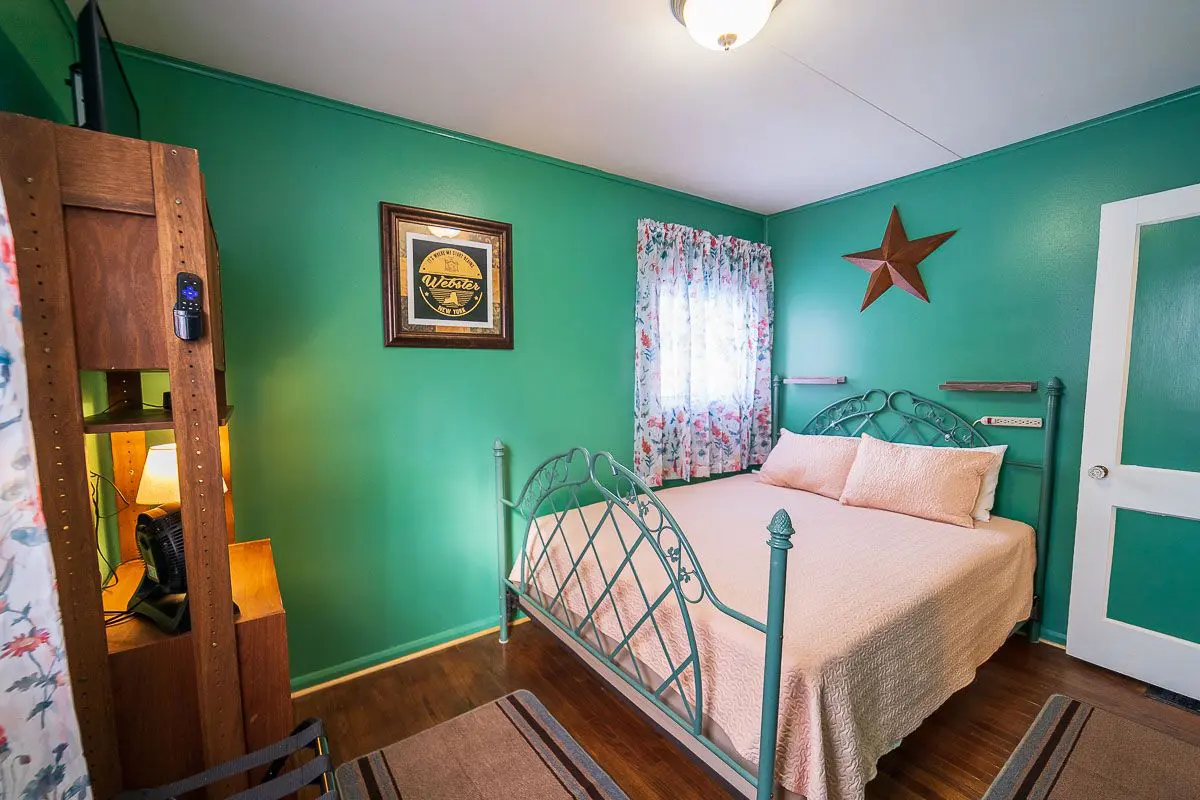 A bedroom with green walls and white bed.